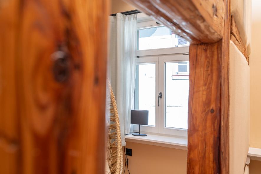 Fachwerkbalken im Hintergrund ein historisierendes Fenster aus Holz in der Pension Grüner Baum